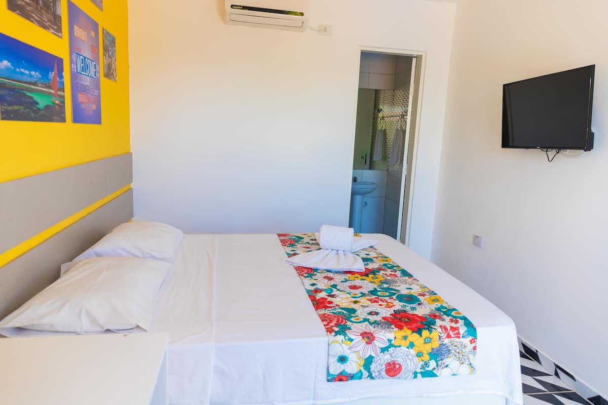 Une chambre d’hôtel équipée d’un lit, d’un téléviseur à écran plat et d’une porte donnant accès à une salle de bain.