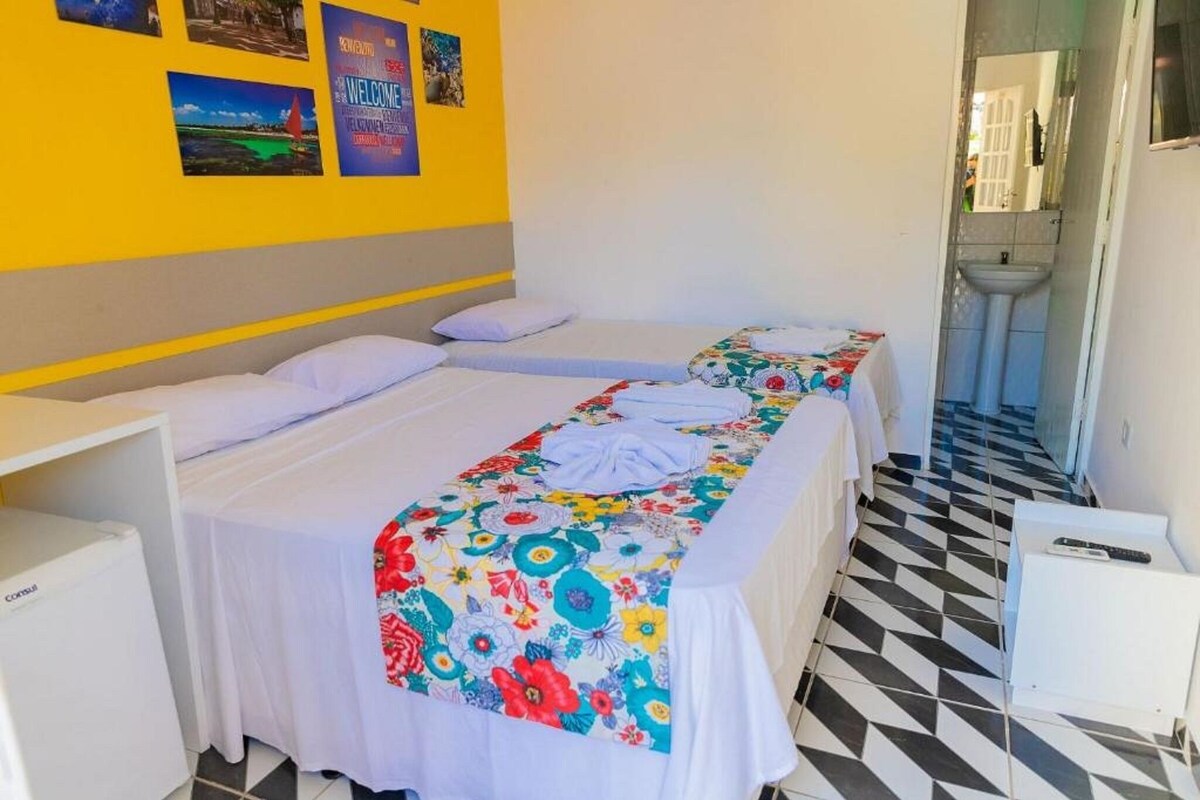 A hotel room with two beds, a bathroom, and a tiled floor.