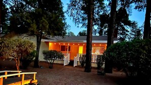 Una casa con una terraza de madera y un camino de piedra que lleva a un portón blanco.