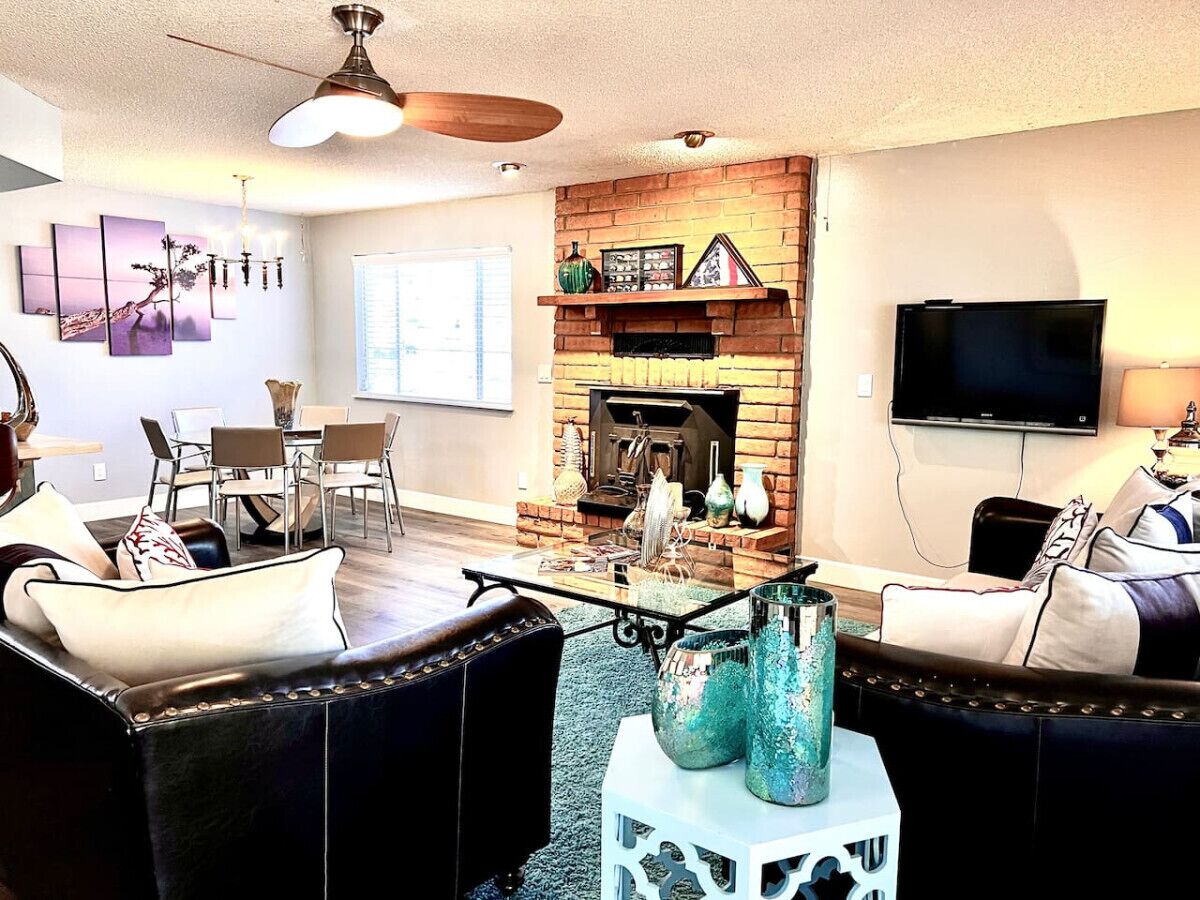 A living room with a fireplace, a television, and a dining area with chairs.