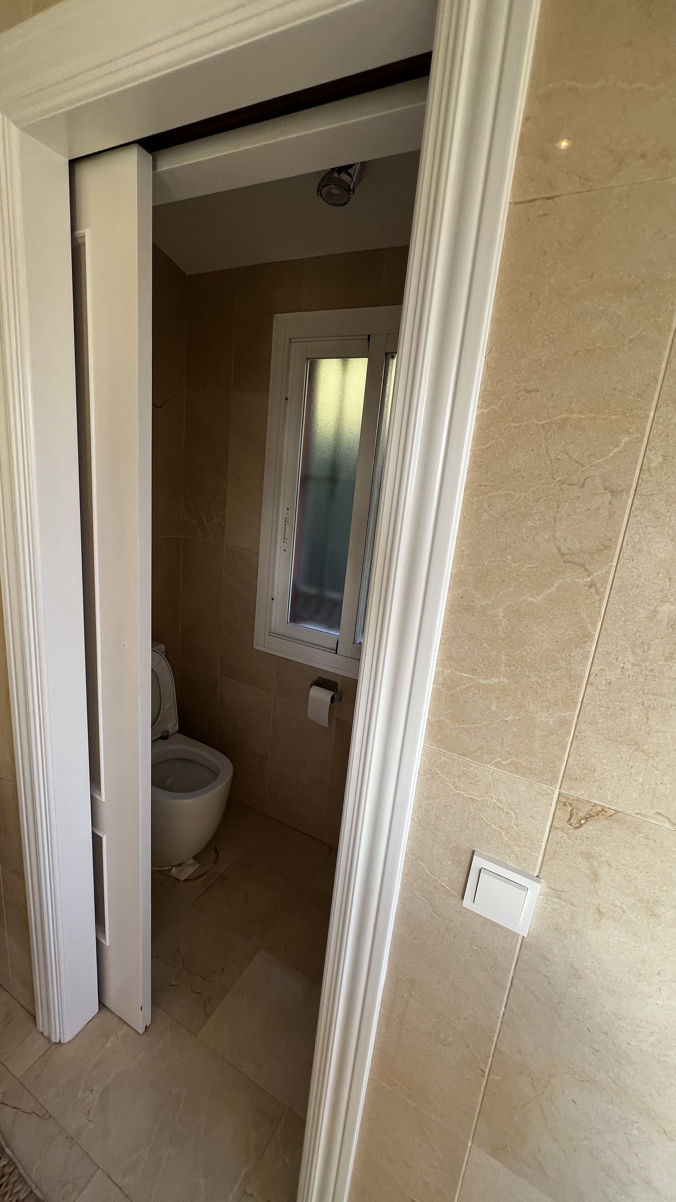 Ein Badezimmer mit Toilette, Dusche und Fenster.