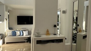 A spacious living area with a modern white entertainment unit, a large flat-screen TV, and a chandelier. - Luxurious sea view villa for 6 people, 1km from the beach (Marbella)