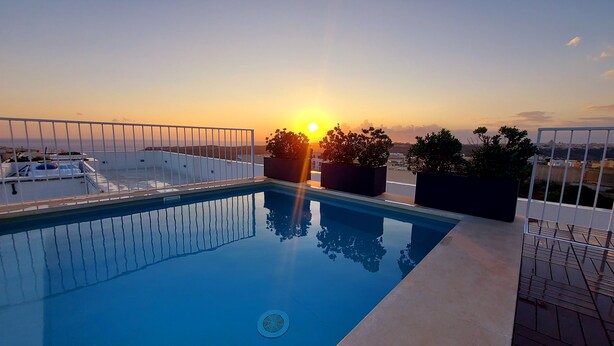 A rooftop pool with a clear view of the sunset, surrounded by potted plants and a white railing. - Penthouse with Private Roof Top Pool (Ix-Xaghra)