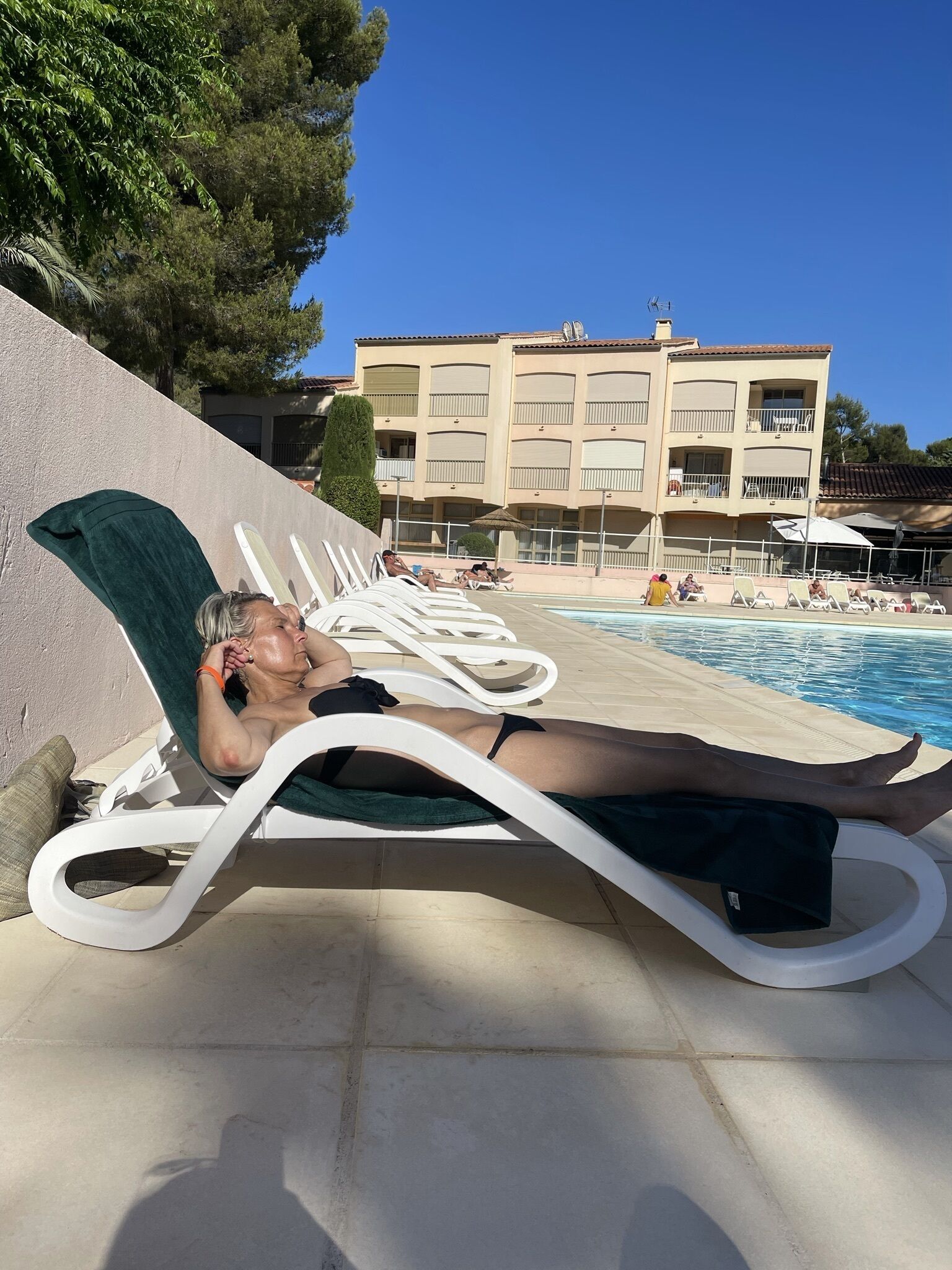 Ett område vid poolen med solstolar och en byggnad i bakgrunden.