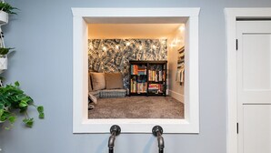 A room with a window wall, a bookshelf, a sofa, and a plant. - A Private Boho-Modern Stay Minutes to Downtown w/ KING Bed and Hidden Nook! (Des Moines)