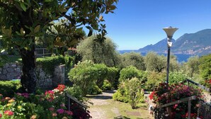 A garden pathway with stone steps, surrounded by lush greenery and flowering plants. - Casa di Alessia THE new vacation apartment with dream view over Malcesine incl. pool (Malcesine)