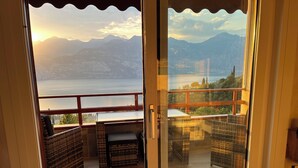 A balcony with wicker furniture, a view of a lake, and mountains in the distance. - Casa di Alessia THE new vacation apartment with dream view over Malcesine incl. pool (Malcesine)