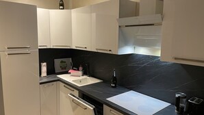 Een moderne keuken met witte kastjes, een zwart marmeren aanrechtblad en een inbouwoven.