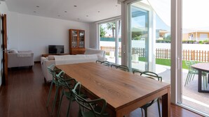 A modern living room with a wooden dining table, green chairs, a white sofa, and a TV. - Villa Houses - Villa Alta Calidad con Piscina y Jardín. A 5 Minutos de la Playa (Ciutadella de Menorca)