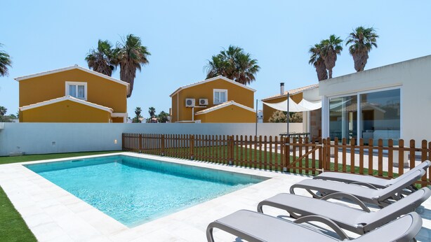 A swimming pool with lounge chairs, a fenced yard, and two yellow houses with palm trees. - Villa Houses - Villa Alta Calidad con Piscina y Jardín. A 5 Minutos de la Playa (Ciutadella de Menorca)