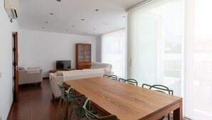 A modern living room with a wooden dining table, green chairs, a white sofa, and a cabinet with glass doors. - Villa Houses - Villa Alta Calidad con Piscina y Jardín. A 5 Minutos de la Playa (Ciutadella de Menorca)