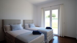 A room with two beds, a sliding glass door to a balcony, and a white ceiling. - Villa Houses - Villa Alta Calidad con Piscina y Jardín. A 5 Minutos de la Playa (Ciutadella de Menorca)