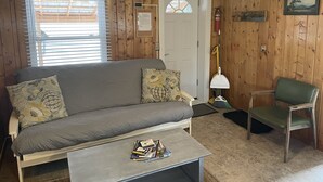 A cozy room with a sofa, a chair, a coffee table, and a door with a window. - Cozy cabin #1 in mountains near Rio Grande River (South Fork)