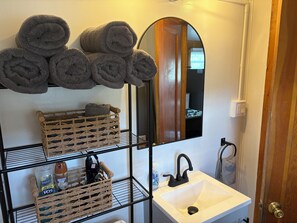 A bathroom with a white sink, a mirror, and towels on a rack.