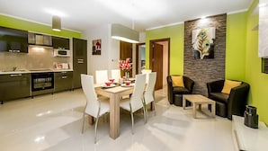 Eine moderne Küche mit Essbereich, ein Wohnzimmer mit Sofa und Couchtisch, und eine Wand mit einem Pfauenfedern-Gemälde.