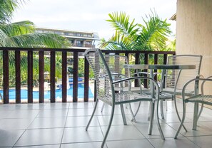Enjoy a refreshing view of the pool and lush surroundings from this balcony.