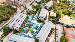 Vista aérea de un complejo turístico con varias piscinas, una playa y varios edificios de hotel.