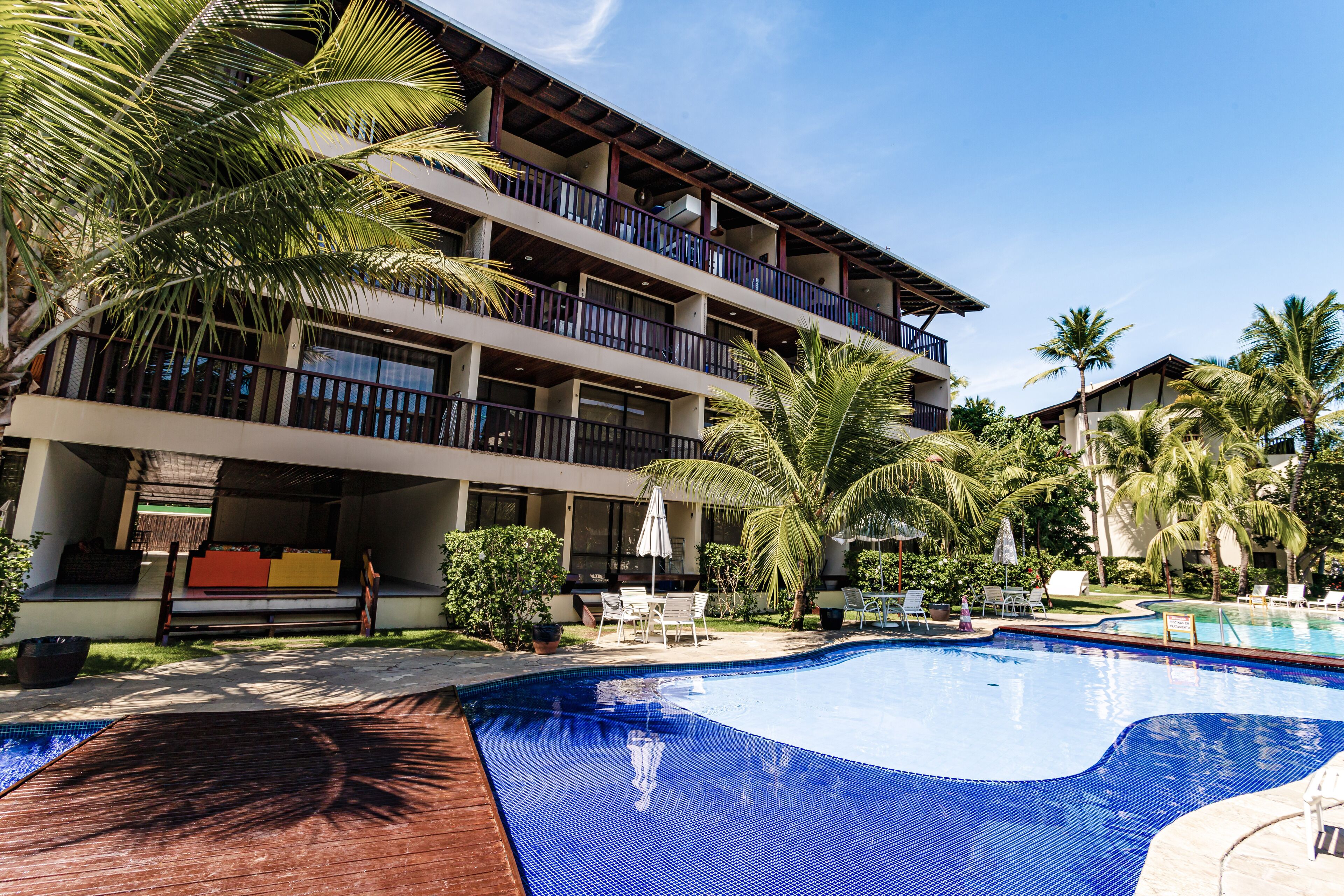 Um hotel com piscina, área de estar ao ar livre e palmeiras.