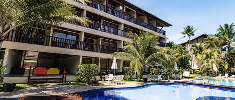 Um hotel com piscina, área de estar ao ar livre e palmeiras.