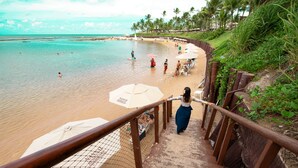 Una escalera que lleva a una playa con sombrillas y gente.