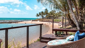 Un patio frente a la playa con mobiliario de mimbre y vista al océano.