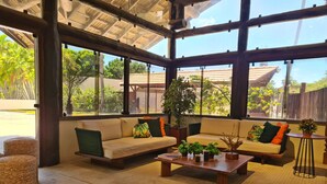 Una habitación amplia con ventanas grandes, un conjunto de sofás y una mesa de centro.