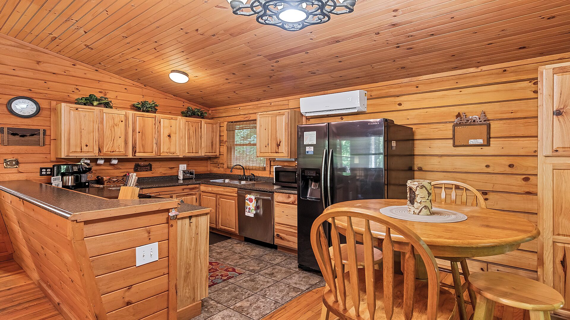 A wooden cabin kitchen with a refrigerator, microwave, coffee maker, and wooden cabinets.