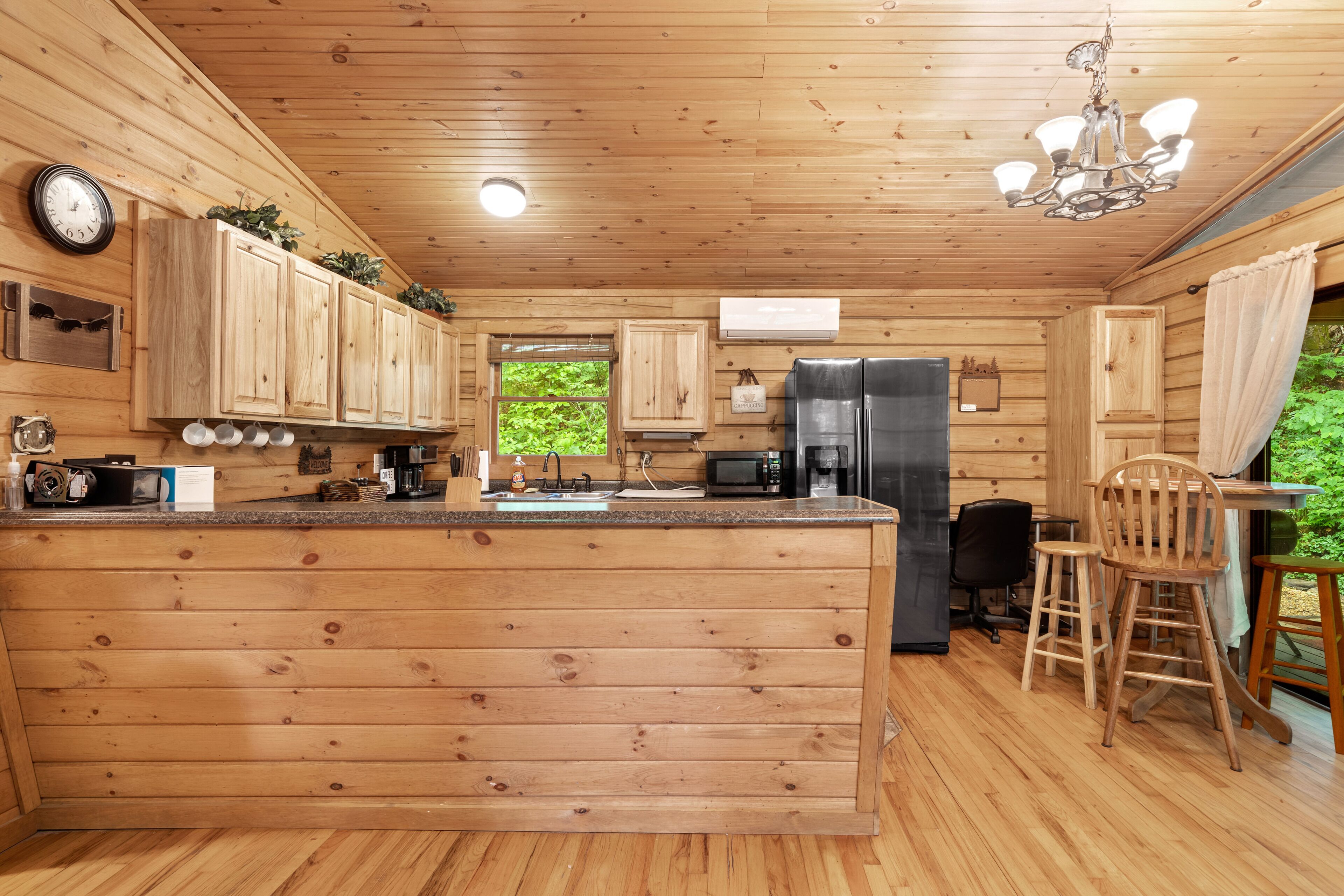 A wooden cabin kitchen with a central island, built-in cabinets, a refrigerator, and a microwave.