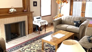 A cozy living room with a fireplace, a sofa, a coffee table, and a patterned rug. - Anna's Bed & Breakfast (Niagara Falls)