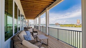 Une terrasse extérieure couverte, aménagée avec des meubles en osier et offrant une vue sur une rivière.