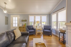 A cozy living room with a dark leather sofa, two matching armchairs, a wooden coffee table, and a small side table with a lamp.