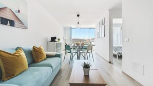 A modern living room with a light blue sofa, a wooden coffee table, and a dining area with a table and chairs. - Home2Book Blue Sea View Patalavaca Beach Apartment (Patalavaca)