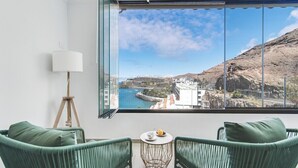 A balcony with a view of a coastal town, a lamp, and two green chairs. - Home2Book Blue Sea View Patalavaca Beach Apartment (Patalavaca)