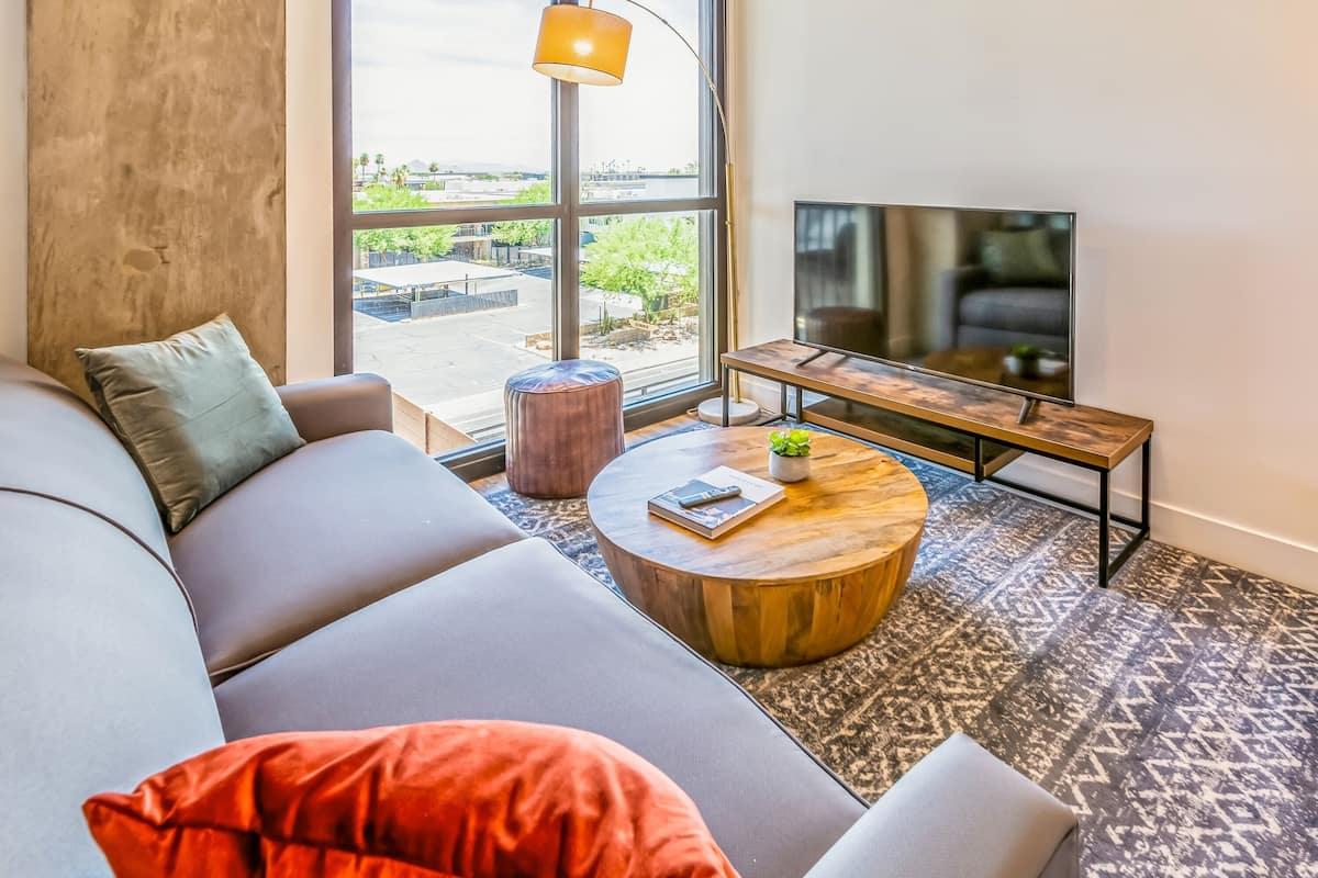 A modern living room with a large window, a sofa, a coffee table, and a TV.