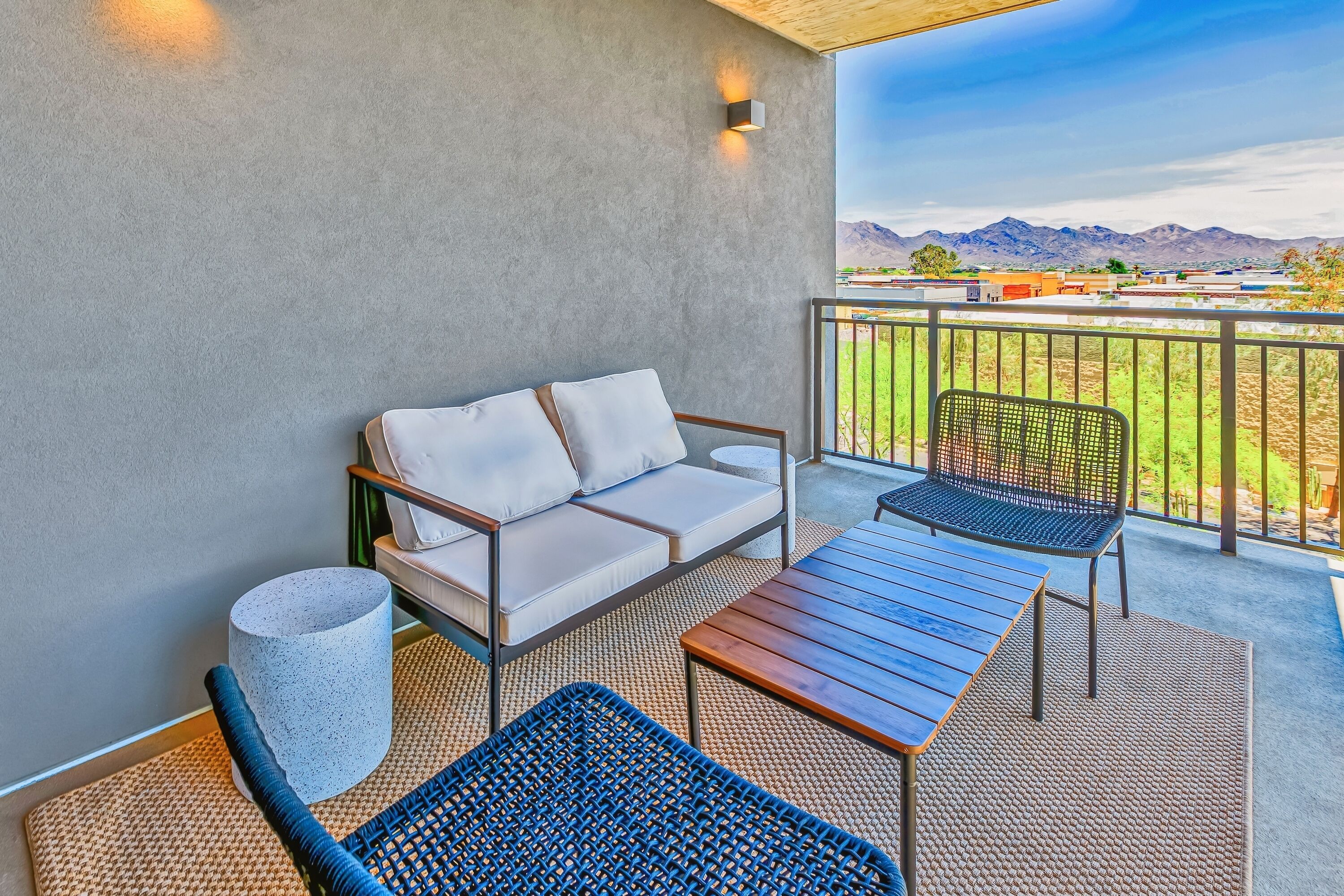 A balcony with a sofa, chairs, and a table.