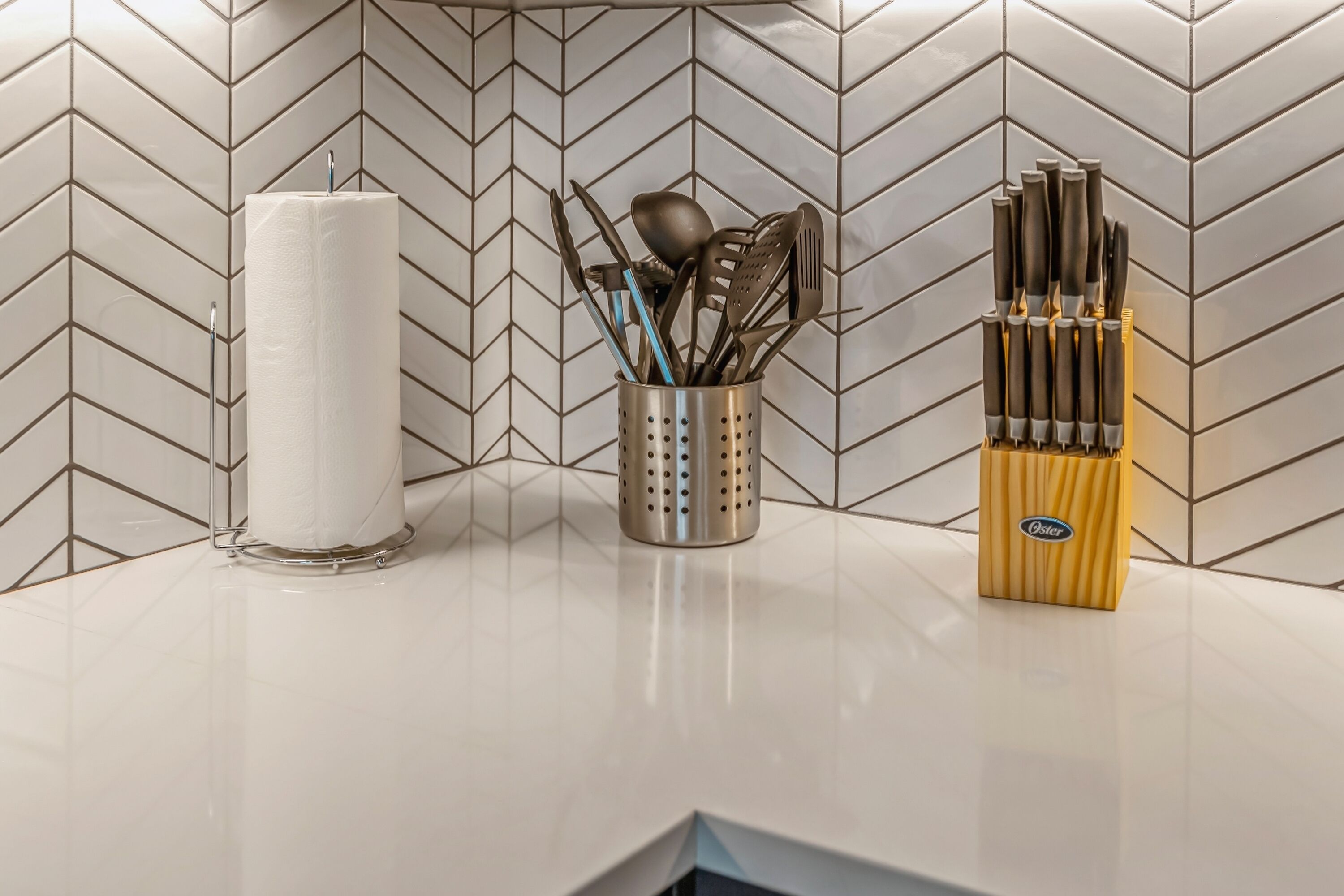 A kitchen counter with a paper towel holder, a utensil holder, and a knife block.