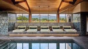 Un área de piscina interior moderna con una zona de estar con vistas a un paisaje idílico.