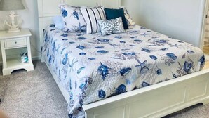 Une chambre à coucher comprenant un lit, une table de chevet, une lampe et une décoration murale en forme d’ancre.