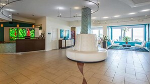 A spacious lobby with a reception desk, a central white pillar, and seating area with a view of the outdoors. - Beautiful Daytona Beach Oceanfront 2 Bedroom Condo (Daytona Beach)