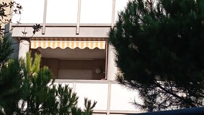 A building with a balcony and a striped awning.