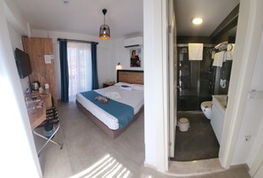 A hotel room with a bed, bedside table, and a shower area. - Picasso Suites Cesme (Cesme)