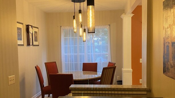 A dining area with a rectangular table, red chairs, and hanging pendant lights. - Serene Townhome minutes away from Christiana Mall, DE Race Park and Univ. of DE (Newark)