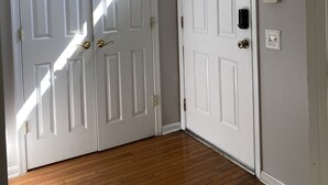A hallway with two white doors, a light fixture, and a thermostat on the wall. - Serene Townhome minutes away from Christiana Mall, DE Race Park and Univ. of DE (Newark)