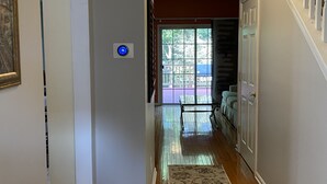 A hallway with wooden flooring, a patterned rug, a ceiling light, and a door leading to a balcony. - Serene Townhome minutes away from Christiana Mall, DE Race Park and Univ. of DE (Newark)