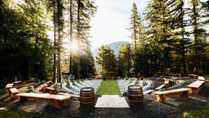 An outdoor seating area with wooden benches and tables, arranged in a semi-circle facing a central path.