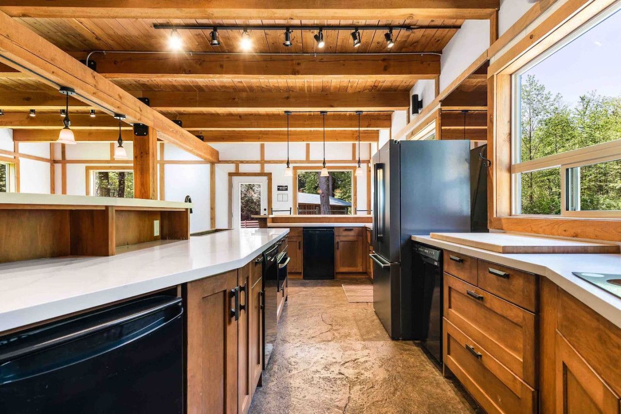Une cuisine moderne avec des poutres en bois, un îlot central et une vue sur l’extérieur.