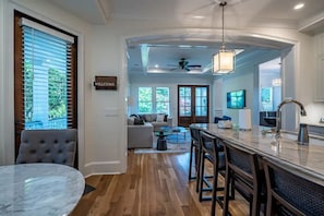 A modern kitchen with a marble countertop, bar stools, and a ceiling fan.
