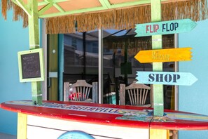 A beachside shop with a surfboard display and directional signs for 'FLIP FLOP', 'REPAIR', and 'SHOP'. - Walk to Clubhouse | Tron Game Room | Tiki Bar | Private Pool | 7BR Villa (Kissimmee)