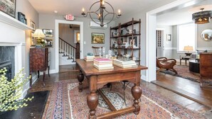 Un salon spacieux avec une table basse en bois, des livres, un lustre et une cheminée.