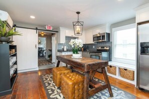 Una cocina moderna con una mesa de madera, taburetes y una lámpara colgante.